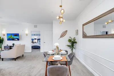a living room with a table and a bedroom at The Secret Rose Apartment - Modern & Stylish - 8 Mins from Disney in Kissimmee