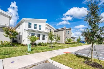 a white house with a tree in front of a street at Chic Luxury Decor Prime Location Game Room Bliss in Kissimmee