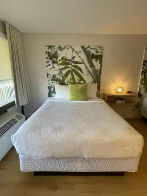 a bedroom with a white bed with a painting on the wall at Newly renovated room in cozy hotel near Disney 2 in Kissimmee