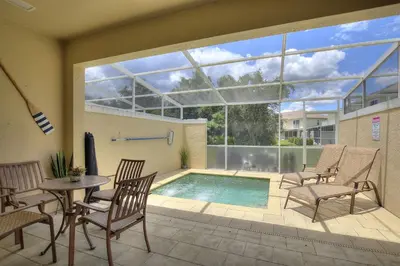 a patio with a pool and chairs and a table at Priceless Peace at Serenity by Shine Villas, 081 townhouse in Orlando