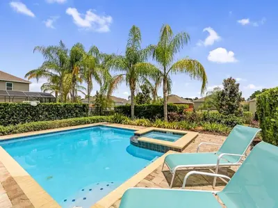 a swimming pool with blue chairs and palm trees at Gorgeous Remo 8 BR at Encore Resort next to Disney in Orlando