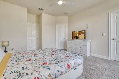 a white bedroom with a bed and a dresser at Distinctive Home Private Pool in Orlando