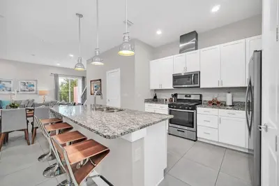 a kitchen with white cabinets and a marble counter top at Magical Residence Resort, 5 min Disney in Orlando