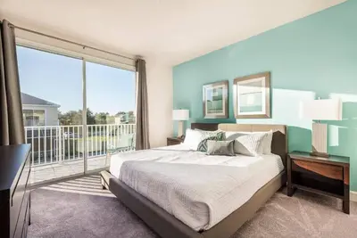 a bedroom with a large bed and a balcony at Super cozy home with private pool in Orlando