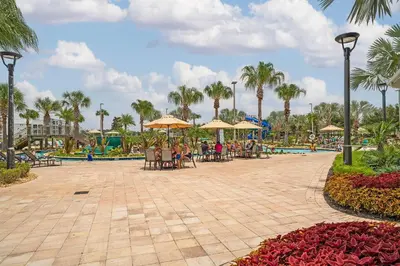 a patio with tables and umbrellas at a resort at Poolside Paradise at Storey Lake: 2-Bedroom in Kissimmee