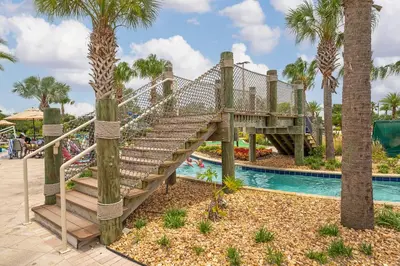 a bridge over a pool at a resort with palm trees at Poolside Paradise at Storey Lake: 2-Bedroom in Kissimmee