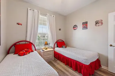 a bedroom with two beds with red sheets and a window at Mickey's Whimsical Wonderland in Kissimmee