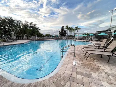 a large swimming pool with lounge chairs at Windsor Palms, next to clubhouse in Kissimmee