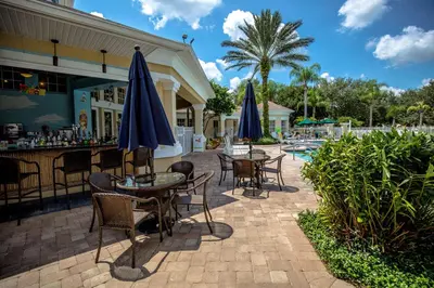 a patio with tables and umbrellas next to a pool at Windsor Palms, next to clubhouse in Kissimmee