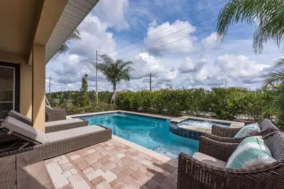 a swimming pool with wicker chairs next to a house at 411-IBRHAIM · 411 Sparkling Spotless Villa in Encore in Orlando
