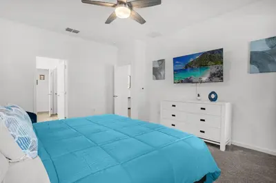 a white bedroom with a blue bed and a ceiling fan at Super Deal - Brand New Themed 9BR Home near Disney in Kissimmee