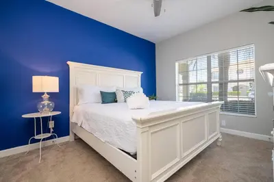 a bedroom with a white bed and a blue wall at Family Fun with Mickey and Frozen at Storey Lake in Kissimmee