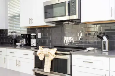 a kitchen with white cabinets and a black stove top oven at Super Luxury Modern Home, Prime Location in Kissimmee