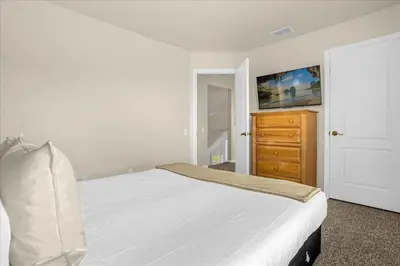 a bedroom with a white bed and a wooden dresser at Luxury 4BR Home at Ventura Golf and Country Club in Orlando