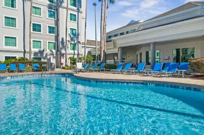 a swimming pool with blue lounge chairs and a building at 5 Minutes to Disney Free Shuttle King & queen bed in Orlando