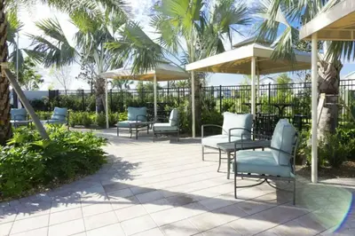 a patio with chairs and umbrellas and palm trees at Premium Apartment 2BR2BA • Near Disney • PoolLazy River at Storey Lake Resort SL47316 in Kissimmee