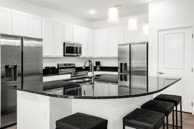 a black and white kitchen with stainless steel appliances at Upstay Ultimate Orlando Retreat w Pool & Hot Tub Sleeps 16 in Kissimmee