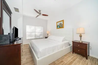 a white bedroom with a bed and a television at Enchanted Townhome near Disney Parks 3Br in Kissimmee
