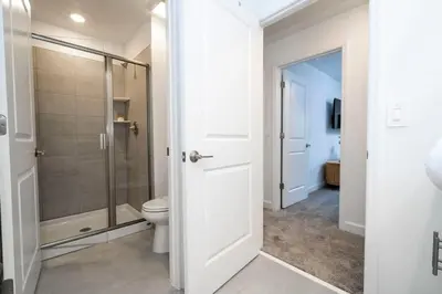 a white bathroom with a shower and a toilet at Gorgeous 4 Bd w Pool at Storey Lake Resort 2485 in Kissimmee