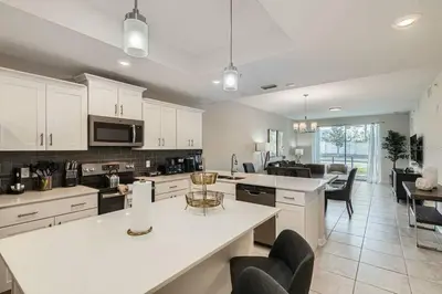 a large kitchen with white cabinets and a living room at Modern Apartment 2BR2BA • Near Disney • Storey Lake Resort SL47314 in Kissimmee