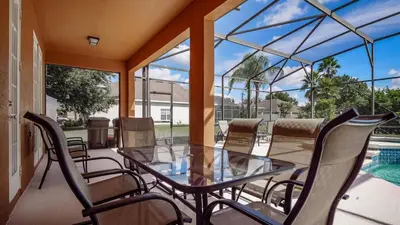 a screened porch with a glass table and chairs at Tranquil Formosa Gardens Villa in Orlando