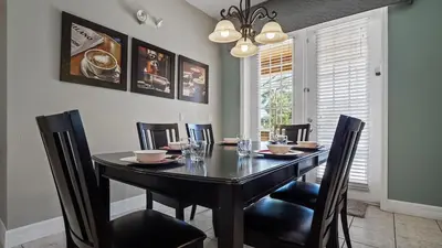 a dining room with a black table and chairs at Tranquil Formosa Gardens Villa in Orlando