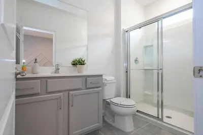 a white bathroom with a toilet and a shower at Brand New Top Elegance Home at Paradiso 6086 in Orlando