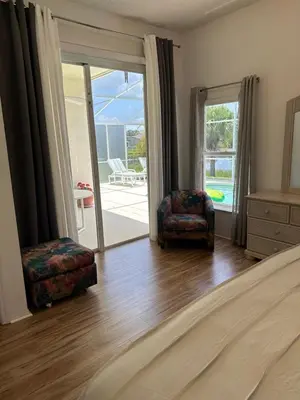 a bedroom with a bed and two chairs and a sliding glass door at Private pool with a beautiful view overlooking the lake! Near Disney - Universal in Kissimmee