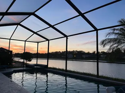 a swimming pool in a glass house with a view of the water at Its A Dream Family Vacation Rental - Minutes from Disney in Kissimmee