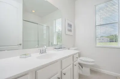 a white bathroom with a sink and a toilet at Premium Comfort - Beautiful Home Private Pool in Kissimmee