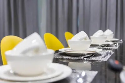 a table with white cups and plates and yellow chairs at Comfy Modern House w Pool Perfect Location in Orlando