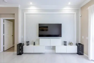 a white living room with a tv on a wall at 4br House w Perfect Location Pool and Much More in Kissimmee