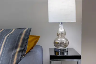 a glass lamp sitting on a table next to a couch at 4br House w Perfect Location Pool and Much More in Kissimmee