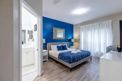 a bedroom with a bed and a blue wall at 4br House w Perfect Location Pool and Much More in Kissimmee
