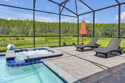 a swimming pool with two chairs and an umbrella at NEW Themed 10B VillaPoolSpa in Kissimmee