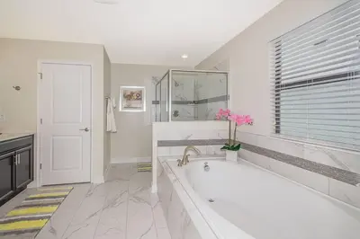 a large white bathroom with a tub and a window at Luxury Villa inside Storey Lake, Kissimmee - No Extra Fees in Kissimmee