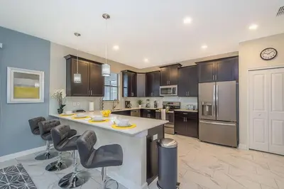 a large kitchen with a large island with bar chairs at Luxury Villa inside Storey Lake, Kissimmee - No Extra Fees in Kissimmee