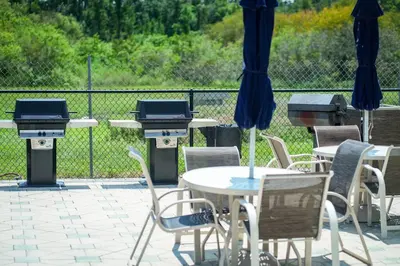 a patio with tables and chairs and a grill at Orlando Apt 9th Floor 5 min from Disney in Orlando