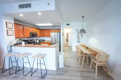 a kitchen with wooden cabinets and a table and chairs at Orlando Apt 9th Floor 5 min from Disney in Orlando