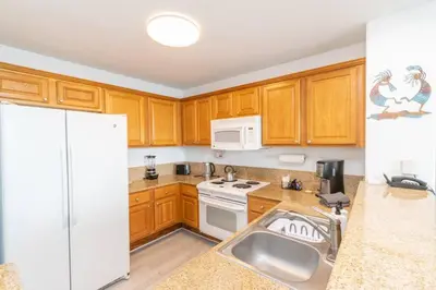 a kitchen with wooden cabinets and a white refrigerator at Orlando Blue Heron condo 1 mile from Disney in Orlando