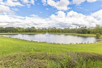 a large pond in a grassy field with a cloudy sky at Amazing Disney Themed Oasis 3BR near Parks townhouse in Orlando
