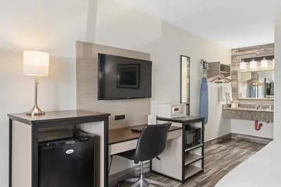 a hotel room with a desk and a television on a wall at Baymont by Wyndham Orlando Downtown in Orlando