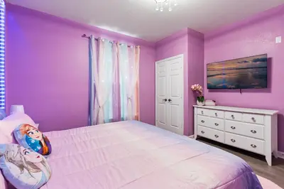 a purple bedroom with a large bed and a dresser at Amazing Apartment 3Brdm - 5 miles from Disney in Kissimmee