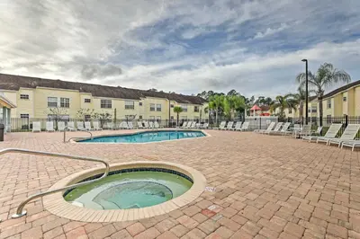 a pool in a brick courtyard with chairs and a building at 6 Mi to Disney Family-Friendly Condo in Kissimmee in Kissimmee