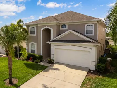 a house with a garage and a palm tree at The Dream Vacation Home! in Orlando