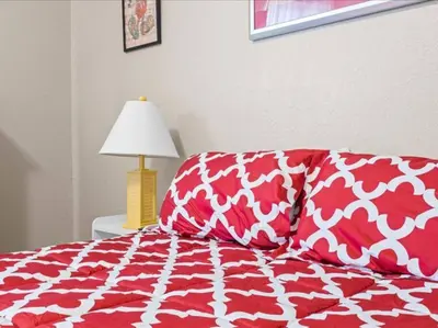 a bed with red and white pillows and a lamp at Theme Park Paradise! in Kissimmee