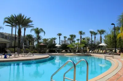 a pool at a resort with palm trees and chairs at Vista Cay Hideway Luxury Home By Universal Orlando in Orlando