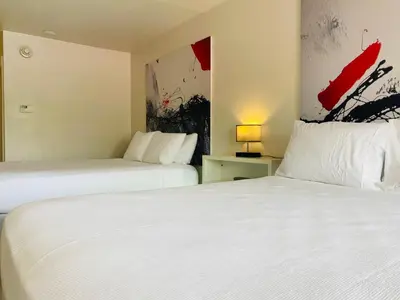 a hotel room with two beds and a painting on the wall at A & S Vacation Rooms in Kissimmee