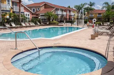 a large swimming pool in a resort with chairs at Charming 3BR home in Kissimmee with private pool and lake view, perfect for families. in Kissimmee