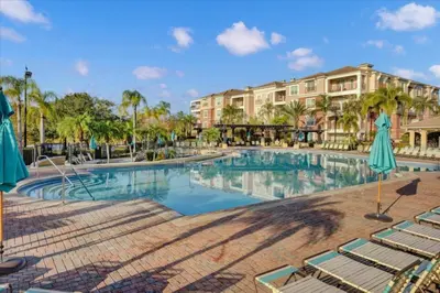 a swimming pool at a resort with chairs and palm trees at Vista Cay Getaway Luxury By Universal Orlando in Orlando